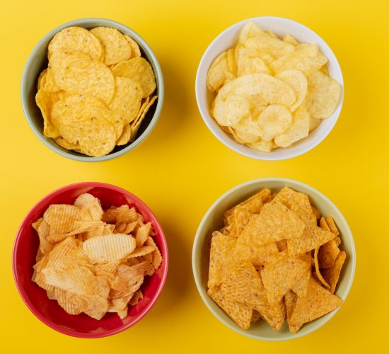 Directly above shot of various snacks in bowls on yellow background